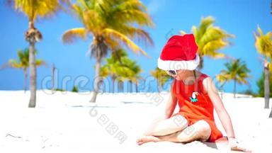 圣诞假期在热带海滩戴着红色圣诞帽的小可爱女孩